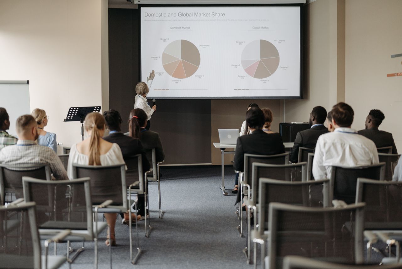 Corporate event production — audience seated at a business conference watching a presentation